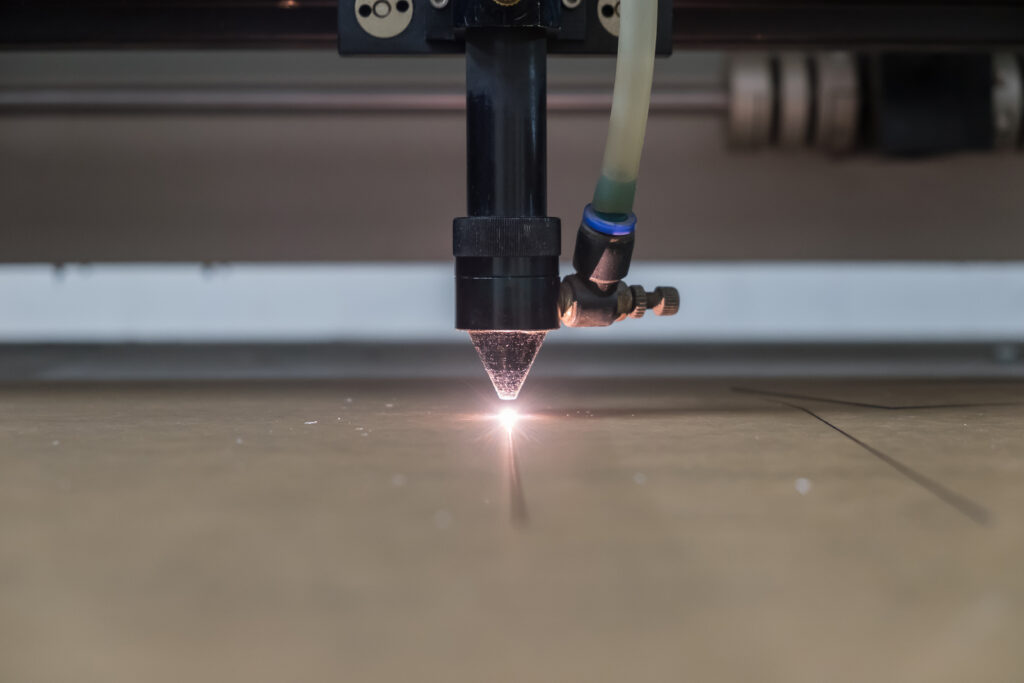 Laser machine engraving a pattern on acrylic sheet.