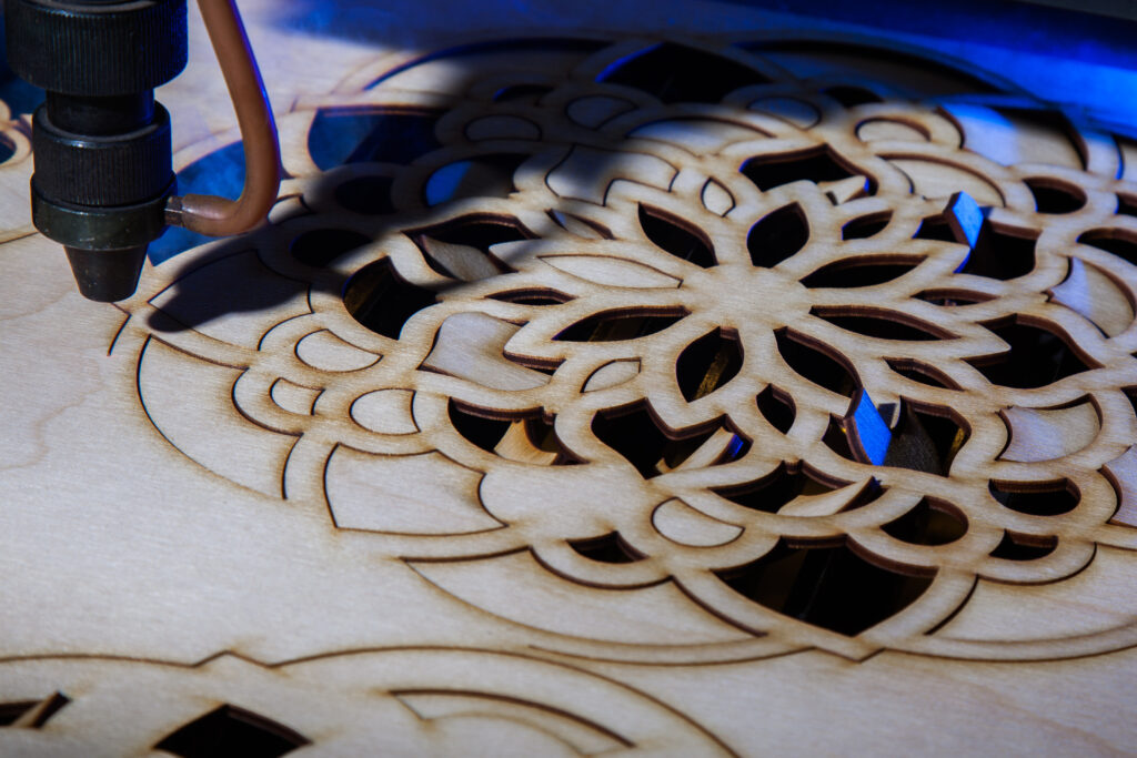 Image of a laser cutting out a mandala pattern on wood.