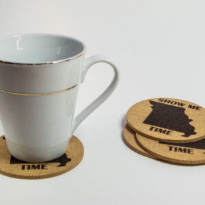 Cork coasters, engraved with the state of Missouri shape and the words "Show Me Time". 3 stacked and one under a glass mug.