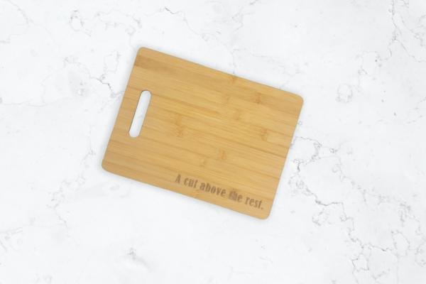 Bamboo cutting board with handle cutout on left side, engraved with the words "A cut above the rest" at the bottom-right.