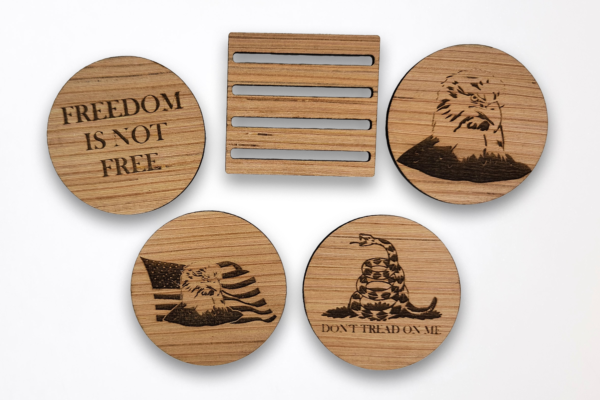 Wooden coasters, arranged around the stand, featuring a bald eagle head, "Don't tread on me" text and snake, Bald eagle in front of the American flag, and the text "freedom is not free.