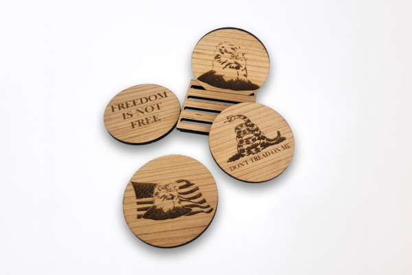 Wooden coasters, arranged around the stand, featuring a bald eagle head, "Don't tread on me" text and snake, Bald eagle in front of the American flag, and the text "freedom is not free.