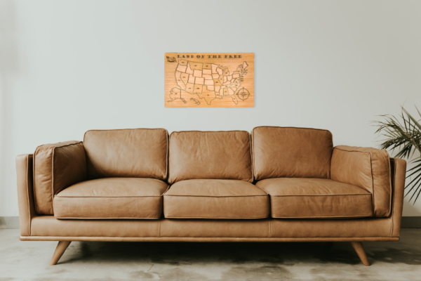 Wooden United States map puzzle hanging on wall above sofa. Some pieces are removed from the frame.