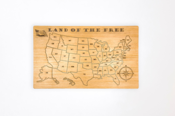 Wooden United States map puzzle, with the words "Land of the free" across the top and a graphic of a bald eagle in front of the American flag in the top left corner.