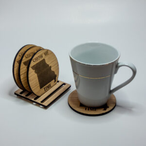 Wooden coasters, engraved with the state of Missouri shape and the words "Show Me Time". 3 on the stand and one under a glass mug.