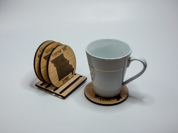 Wooden coasters, engraved with the state of Missouri shape and the words "Show Me Time". 3 on the stand and one under a glass mug.