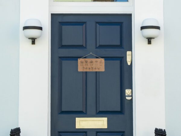 Wooden sign laser engraved with ASL handshapes, fingerspelling: Miner Family. Sign is hung on a blue door.