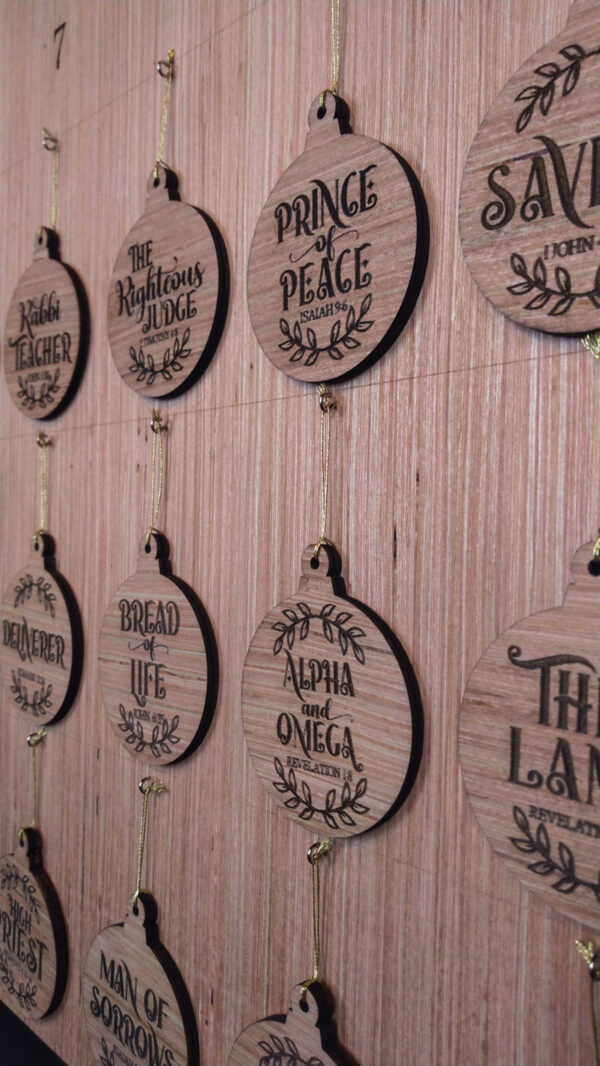 Close up of a wooden Advent calendar with ornaments featuring the names of Jesus Christ.