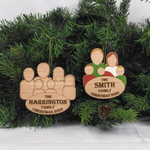 Two wooden family group ornaments hanging on pine boughs. One ornament is painted and features five characters and the words: The Smith Family, Christmas 2022. The second ornament is unpainted and features six characters and the words: The Harrington Family, Christmas 2022