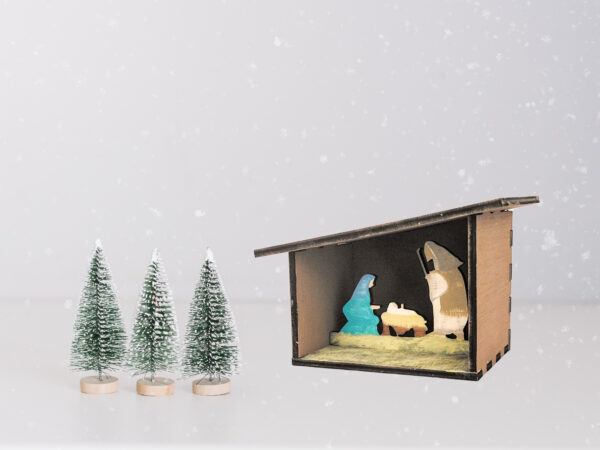 Painted 3D Nativity scene with a snowy background and small pine tree figures.