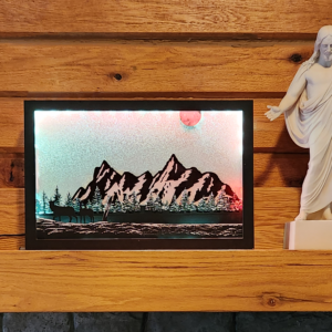 Beautiful 3d lightbox featuring a snowy mountain scene with a glittery white background reflecting the light through the scene. Lightbox is displayed on a mantle.