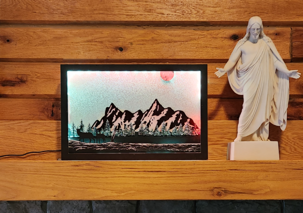 Beautiful 3d lightbox featuring a snowy mountain scene with a glittery white background reflecting the light through the scene. Lightbox is displayed on a mantle.