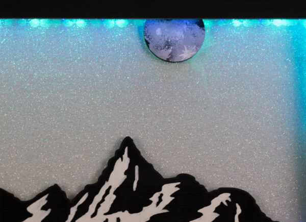 Closeup of mountaintop and full moon with the glittery white background reflecting the soft blue light through the scene.