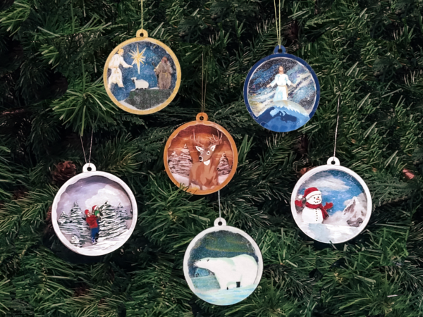 Christmas snow globe ornaments hanging on pine boughs. Six different designs are shown.