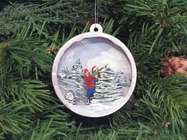 Finished Christmas tree snow globe ornament hanging on pine boughs.