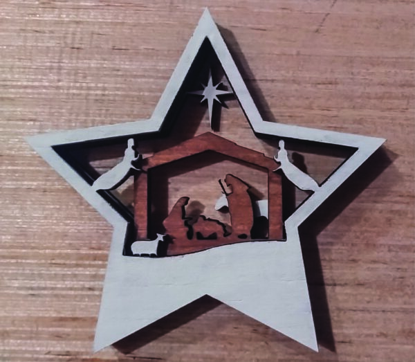 Star shaped, layered 3D Nativity Christmas tree ornament, featuring the holy family in a stable, with, angels, sheep, donkey and star. Wood background.